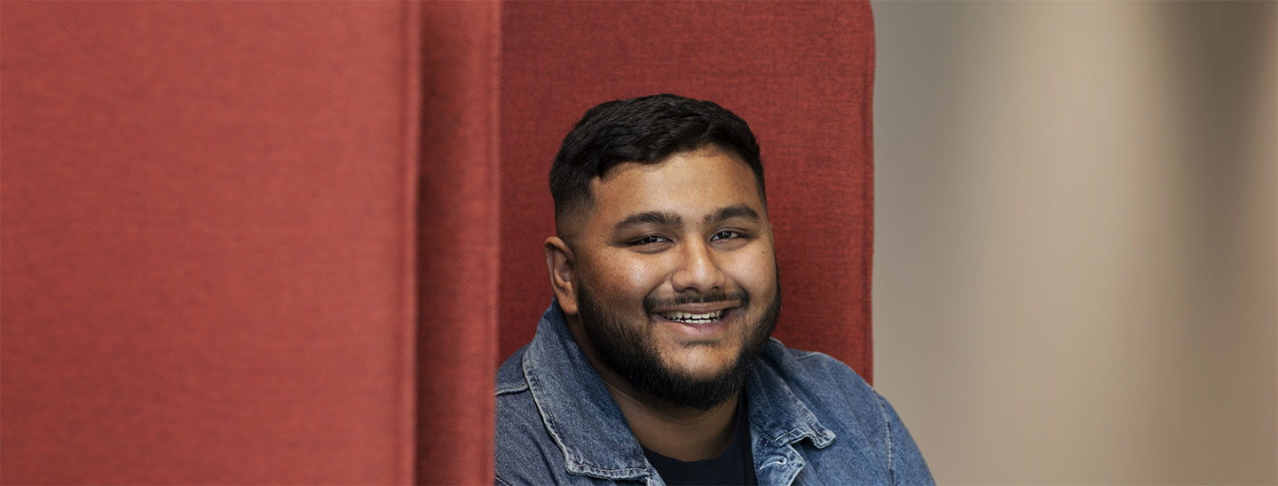 Male student on campus sitting couch happy