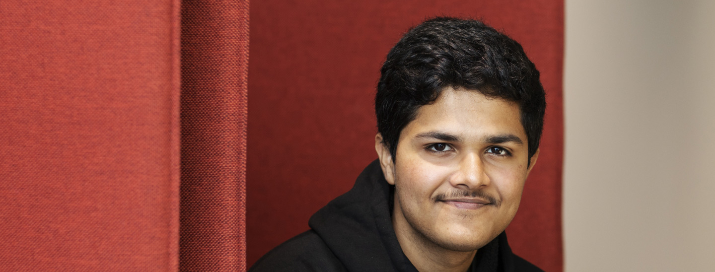 Male student sitting red couch