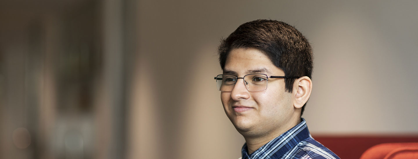 Male student wearing glasses red couch