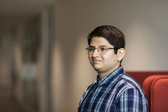 Male student wearing glasses red couch